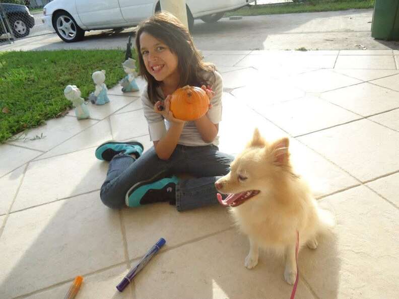 Una niña posa con su perro en su jardín.