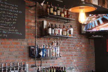 Cedar Point Bar & Kitchen's exposed brick barroom, with shelves built from pipes and TV broadcasting ESPN