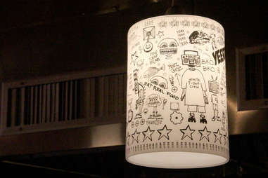 Street art-covered lamps hang over the noodle bar counter.