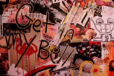 Graffiti on the decoupaged back wall reads "Get in my belly"
