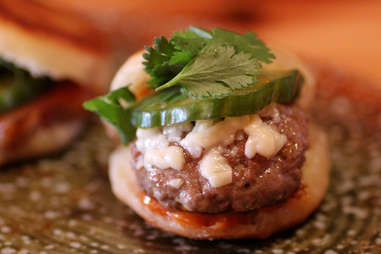 A pickle-topped cheeseburger slider on an English muffin bun.