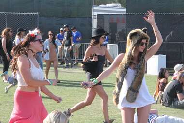 Two girls dance as another runs by at Coachella 2013