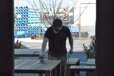 An employee sanding tables outside Rye in Louisville