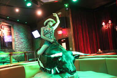 A girl rides a mechanical bull at Buck Wild's, Los Angeles