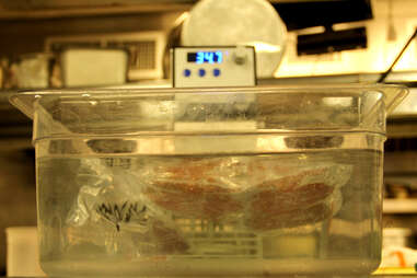 Sealed burger is slow-cooked sous vide in a water bath.