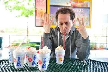 guy eats a strawberry cheesecake milkshake at Sonic