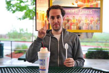 guy eating a strawberry milkshake at Sonic