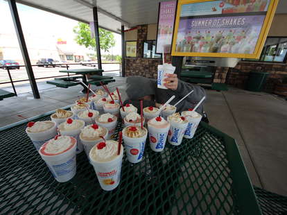 guy holding up a milkshake at Sonic