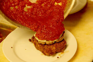 Marinara sauce is poured from the pan onto the Lasagna Burger at PYT.