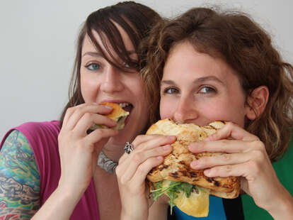 Two girls eat a herring slider and a lamb cheeseburger at Noord