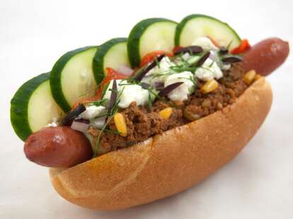 Hot dog with chili, cucumbers and feta cheese
