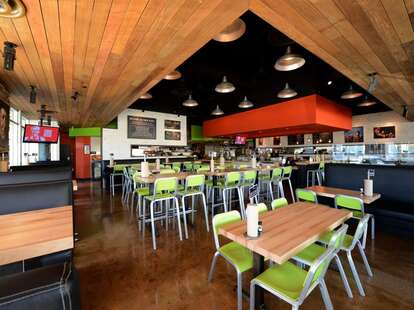 Interior of Hopdoddy with wood floors and ceilings and lime green chairs.