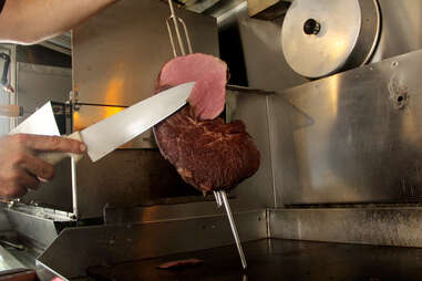 Slicing meat atop the grill inside the Braz BQ Truck