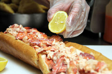 Adding lemon juice to the USS Lobstitution lobster roll at Pauli's North End