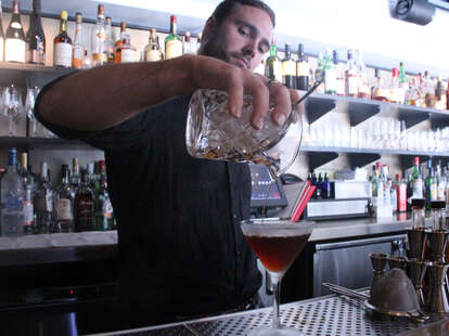 a bartender pours a rye cocktail at a.bar