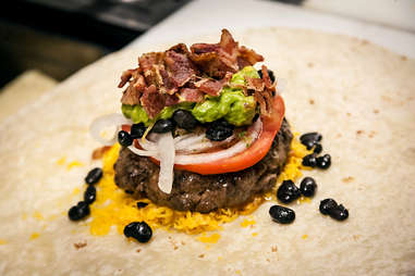 Crumbled bacon is added to the Supreme Nacho Burger at Slater's 50/50 in Liberty Station San Diego.