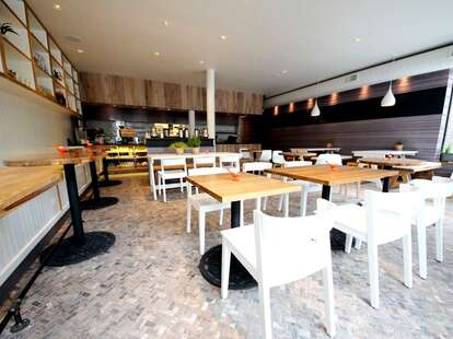 The bright interior at Senza, with various white tables and wooden chairs.