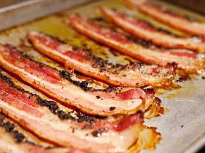 Strip of bacon sizzling on a grill.