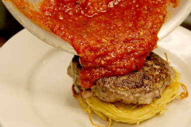 Marinara sauce is poured from the pan onto the Spaghetti Burger at PYT.