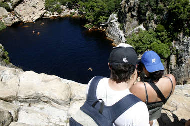 Dudes standing on cliff over water