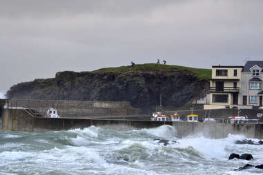 People high up on cliff with crashing surf